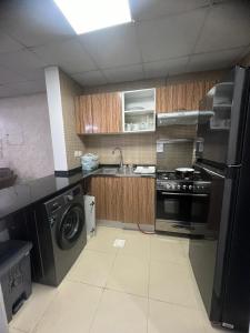eine Küche mit einem Herd, einer Waschmaschine und einem Trockner in der Unterkunft furnished apart in city tower in Ajman 