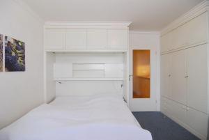 ein Schlafzimmer mit weißen Schränken und einem weißen Bett in der Unterkunft Haus am Meer, Whg 80, Landseite in Westerland