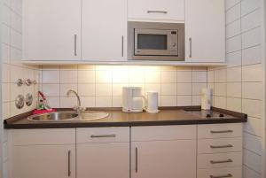 eine Küche mit einer Spüle und einer Mikrowelle in der Unterkunft Haus am Meer, Whg 80, Landseite in Westerland