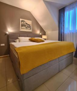 a bedroom with a large bed with a yellow blanket at Aparthotel Gaja in Bled