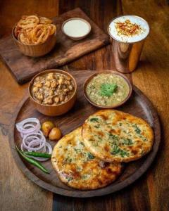 Shiv Shankar Guest House في أمريتسار: طاولة خشبية عليها بيتزا وغيرها من الأطعمة