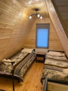 two beds in a attic room with a window at Cottage Pasanauri in Passanauri