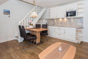 uma cozinha com uma mesa e cadeiras e uma escadaria em Haus Szameit, Whg 3 em Süderende