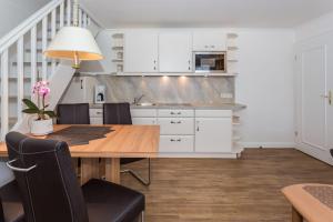 uma cozinha com uma mesa de madeira e armários brancos em Haus Szameit, Whg 3 em Süderende
