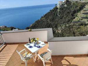 a table and chairs on a balcony with a view of the ocean at Piccola Perla in Amalfi