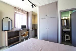 1 dormitorio con cama, escritorio y espejo en Alekos Studios, en Diakofti