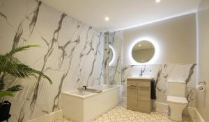 a bathroom with a white tub and a marble wall at WhiskAwayStays - Victoria House - Apartment 4 in Worcester +19 photos