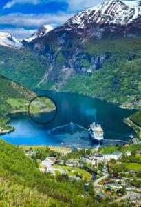 una nave da crociera in un lago tra le montagne di Solhaug Fjordcamping a Geiranger