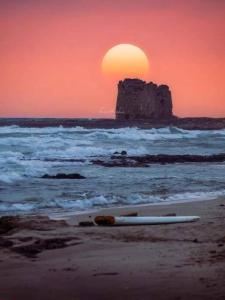 una tabla de surf puesta en la playa con la puesta de sol en La Difisola en Lizzano