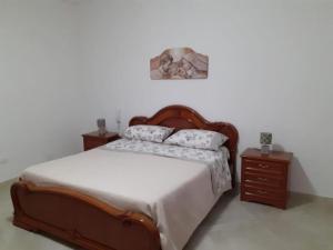 1 dormitorio con 1 cama de madera y 2 mesitas de noche en La Difisola en Lizzano