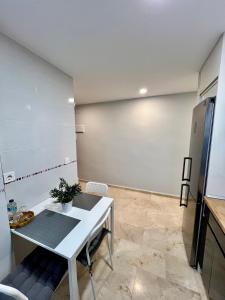 Apartamentos Prestige Málaga Suites IV في مالقة: مطبخ مع طاولة بيضاء وثلاجة