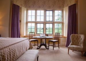 Llangoed Hall في Bronllys: غرفة نوم مع طاولة وكراسي ونافذة