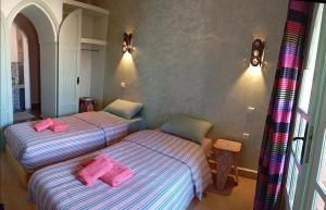 2 letti in una camera con cuscini rosa di Riad tania mozaik a Taroudant