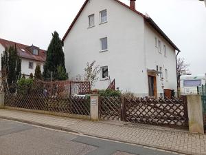 a white house with a fence in front of it at Geräumige FeWo nahe Nürnberg in Oberasbach