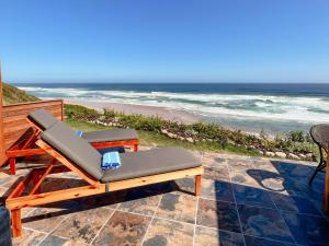 a chair on a patio with the ocean in the background at Mes Amis Beach Guest House in Wilderness