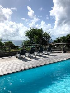 a group of chairs sitting on a deck next to a swimming pool at Domaine Diamant Caraibes in Le Diamant