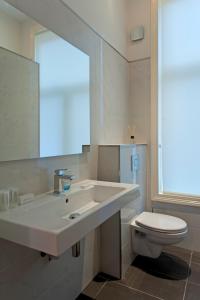 een witte badkamer met een wastafel en een toilet bij Amsterdam Rembrandt Square city center Hotel in Amsterdam