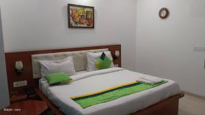 a bedroom with a large white bed with green pillows at Spring Brook by vagmi in Gurgaon