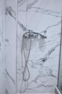 a shower with a hose in a white marble bathroom at SKYLINE Fine Living in Nei Poroi