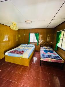 Anong Villa في Nathon Bay: سريرين في غرفة بجدران خشبية ونوافذ