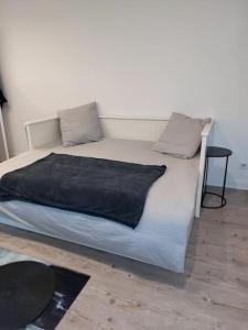 a white bed with a black blanket on it at Charmant studio 17m2 in Élancourt