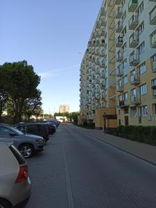 een straat met auto's geparkeerd naast een hoog gebouw bij Uroczy apartament nad morzem Gdańsk in Gdańsk