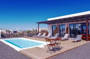 a pool with chairs and a table next to a house at NaoClub Fuerteventura in Lajares