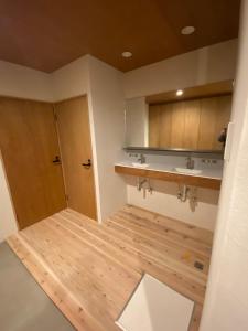 a bathroom with a wooden floor and a sink and a door at Togaku Hokosha Female -over16 years old- Only Guest House - Vacation STAY 15724 in Nagano