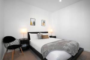 墨尔本Retro Modern with Pool near Westfield Doncaster的一间卧室配有一张床、一把椅子和两盏灯。