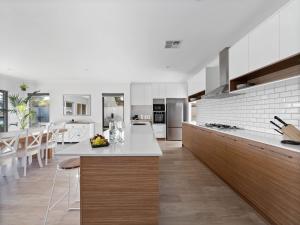 a kitchen with white appliances and a dining room at Mariners Cove Luxury Canal Home in Mandurah