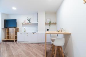 a kitchen with white cabinets and a wooden table at Apartamentos turísticos Fátima, en el centro de Vigo in Vigo +66 photos