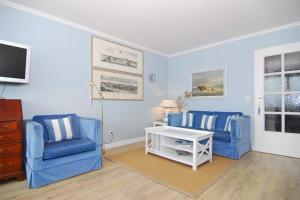 uma sala de estar com duas cadeiras azuis e uma televisão em Metropol, Whg 127, Seeseite em Westerland