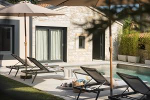 Un grupo de sillas y sombrillas junto a una piscina. en Modern villa Bino&Marija with pool in Porec, en Kirmenjak