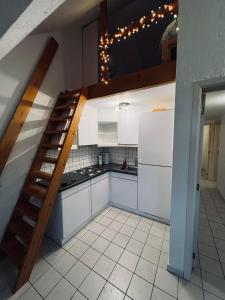 a kitchen with white cabinets and a spiral staircase at Appartement net buiten stadskern in Hasselt