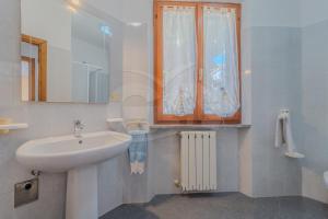 a white bathroom with a sink and a window at La Rondine su Seccheto - Goelba in Seccheto