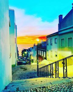 una puesta de sol sobre una calle con edificios y el océano en Just Sezimbra en Sesimbra