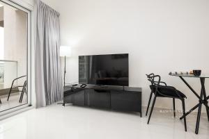 een witte woonkamer met een zwarte kast en stoelen bij The Tranquil Spot in Damac Hills 2 in Dubai