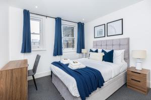 Luxury Harley Street Apartments في لندن: غرفة نوم مع سرير مع ستائر زرقاء ومكتب