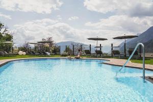 eine Frau neben einem Swimmingpool mit Sonnenschirmen in der Unterkunft Hotel Fürstenhof in Schenna