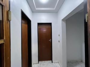 un couloir avec une porte marron et des murs blancs dans l'établissement As résidence meublée, à Ouagadougou