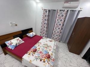 - une petite chambre dotée d'un lit avec des draps et des rideaux floraux dans l'établissement As résidence meublée, à Ouagadougou