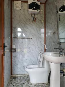 uma casa de banho com um WC branco e um lavatório. em Homstay Mimosa Mộc Châu em Mộc Châu
