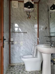 a bathroom with a white toilet and a sink at Homstay Mimosa Mộc Châu in Mộc Châu