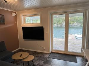 sala de estar con TV de pantalla plana en la pared en Rorbu i Gilsvågen - 3 soverom - Båtutleie en Austevoll