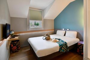 een hotelkamer met 2 bedden en een raam bij ibis budget Cholet Centre in Cholet