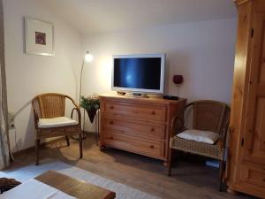 a living room with a tv on a dresser with two chairs at Haus Rappolder - Ferienwohnung in Mittenwald