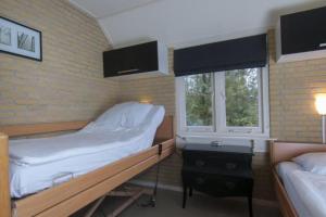 un dormitorio con una cama y una ventana en Bungalow De Schuilevink - 8p MIVA, en Otterlo 20 fotos más