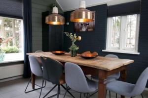 uma sala de jantar com uma mesa de madeira e cadeiras em Bungalow De Schuilevink - 8p MIVA em Otterlo