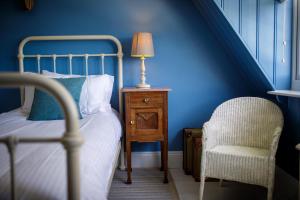 a bedroom with a bed with a lamp and a chair at Lulworth Cove Inn in Lulworth Cove