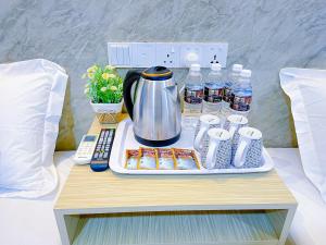 StarQ Hotel Bukit Bintang في كوالالمبور: صينية مع غلاية شاي وزجاجات ماء على طاولة